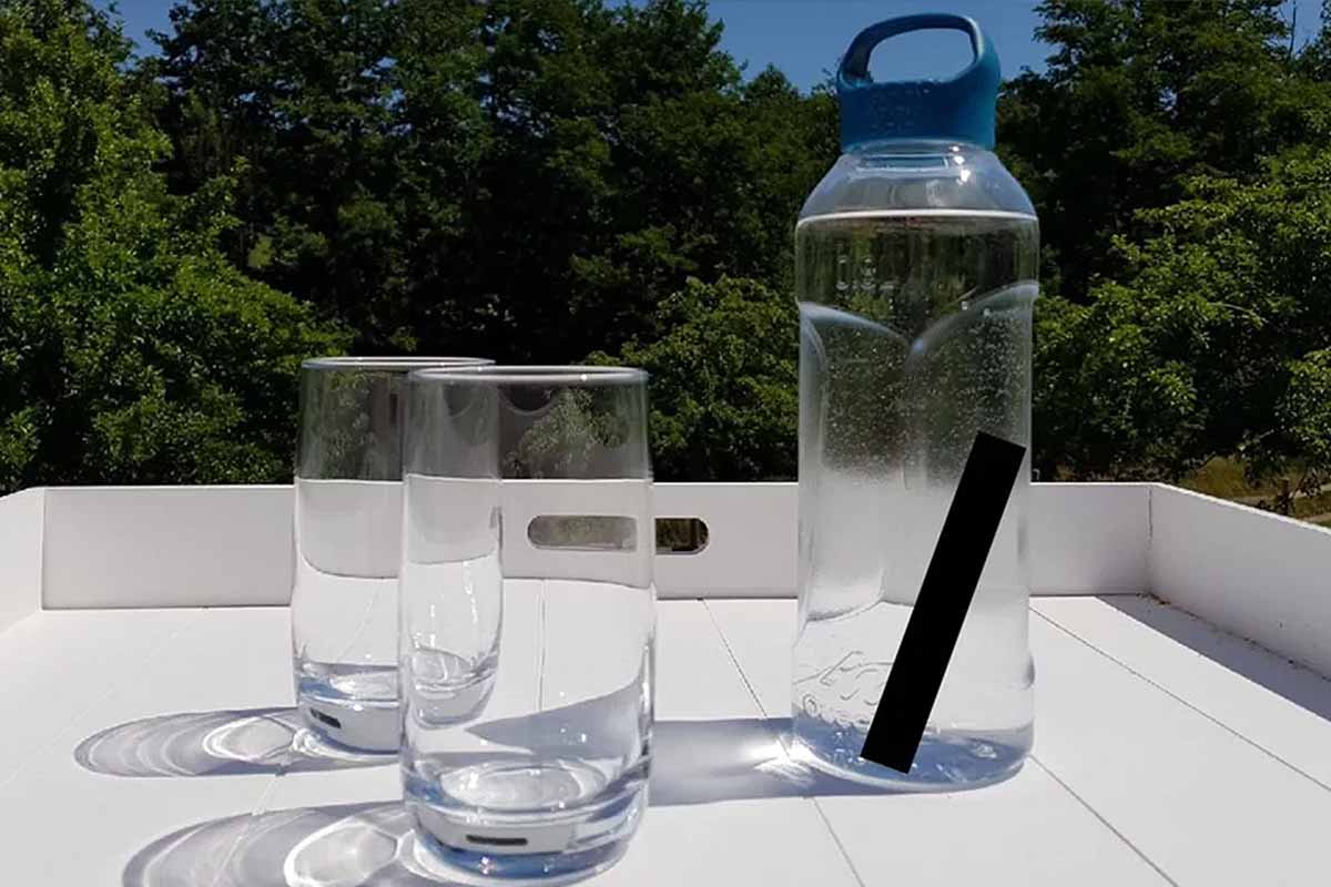 Batonnet de charbon actif filtrant l'eau dans une gourde, à côté de deux verres